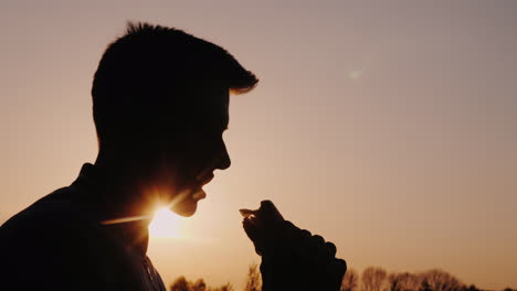 Profil-Eines-Mannes,-Der-Bei-Sonnenuntergang-Einen-Appetitlichen-Burger-Isst