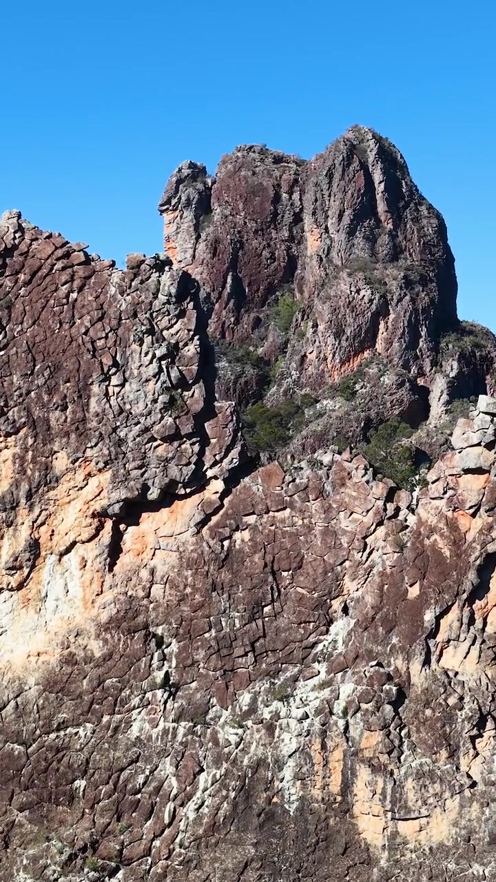 Ampia inquadratura statica di antiche cime vulcaniche sotto un cielo azzurro e limpido a Warrumbungle, Australia