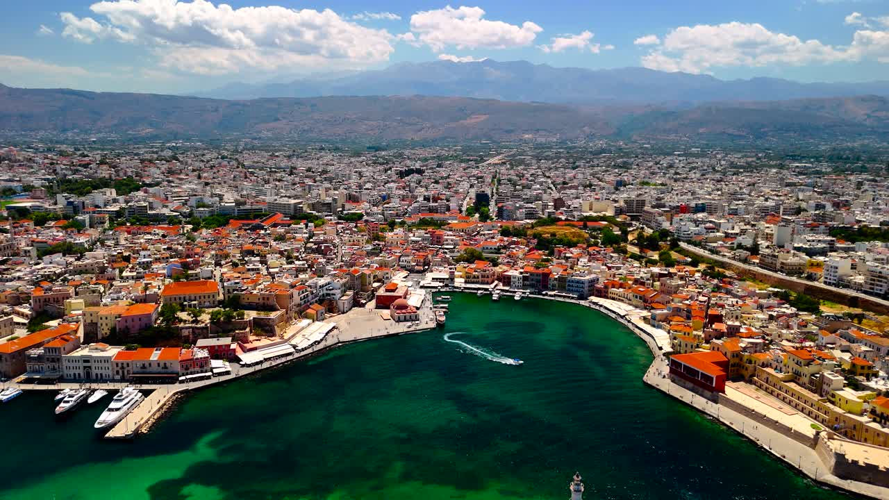 A breathtaking aerial view captures the beauty of a coastal city, featuring colorful buildings along the waterfront, surrounded by mountains and clear skies
