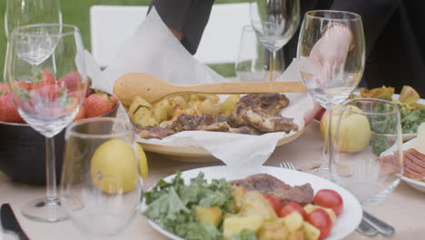 close up of two unrecognizable women setting food on a dining table for an outdoor party in the park