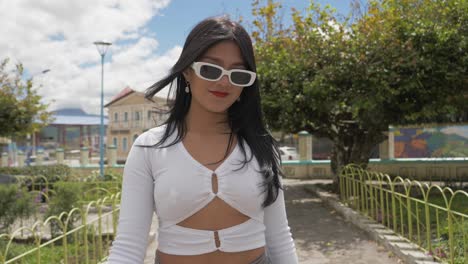 Clip-Cinematográfico-De-Cerca-De-Una-Joven-Latina-Morena-Con-Gafas-De-Sol-Caminando-Hacia-La-Cámara-Con-Confianza