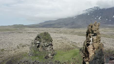 Torres-De-Basalto-Volcánico-En-La-Costa-De-Islandia-Con-Una-Gran-Montaña-En-El-Fondo