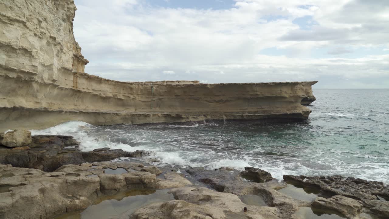 las furiosas olas del mar mediterráneo se estrellan en la playa de piedra de la piscina de san pedro en malta