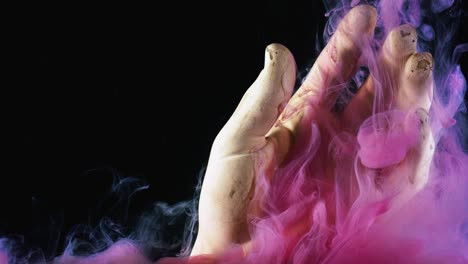primer plano de una nube de tintas rosas brillantes que se extienden bajo el agua alrededor de la mano artificial. imágenes de stock. figura de la mano y pinturas aisladas en fondo negro