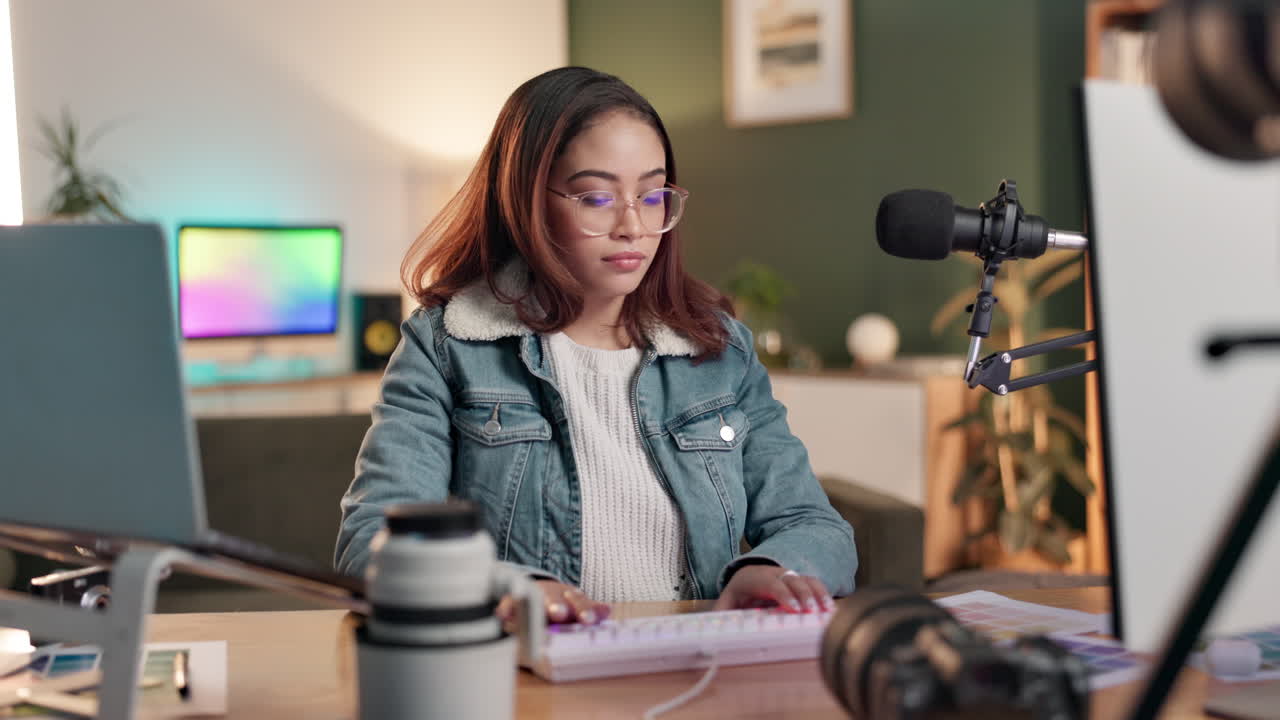Woman working at a desk with computer, microphone and camera