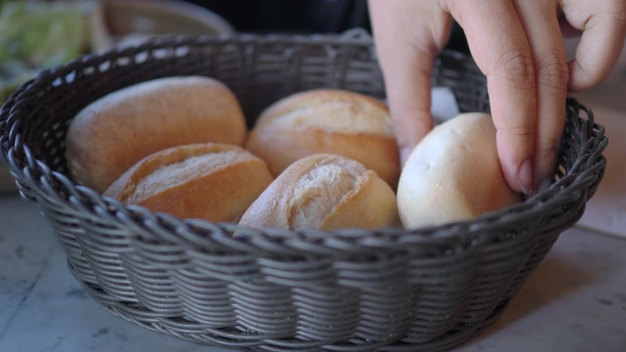 Hand Picking a Fresh Bread Roll from a Wicker Basket