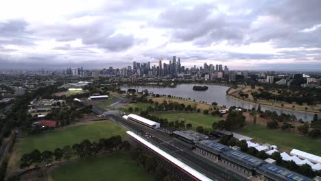 Aerial-Albert-park-lake-with-Melbourne-City-skyline-pit-lane-for-F1-grand-prix,-Australia