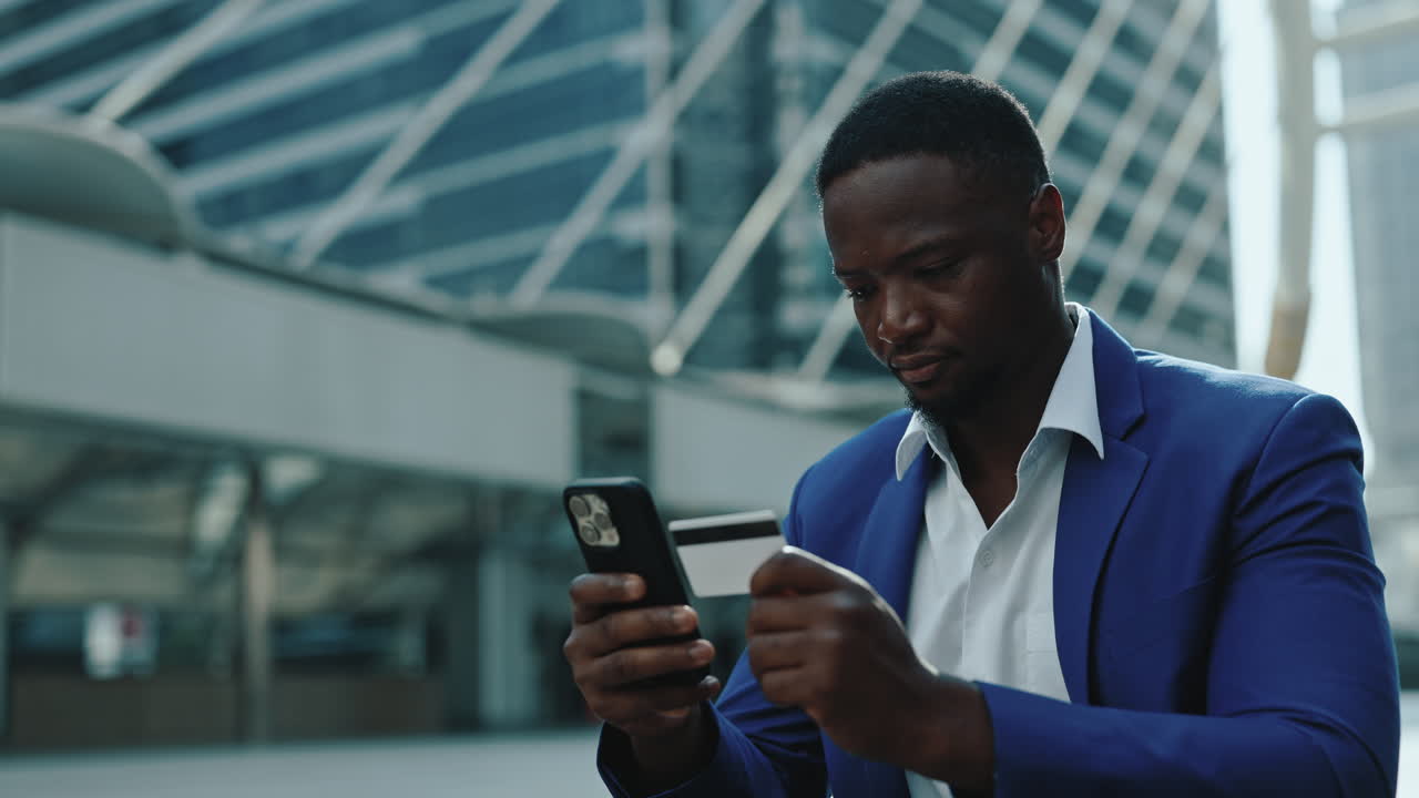 Businessman making online payment with smartphone and credit card in city