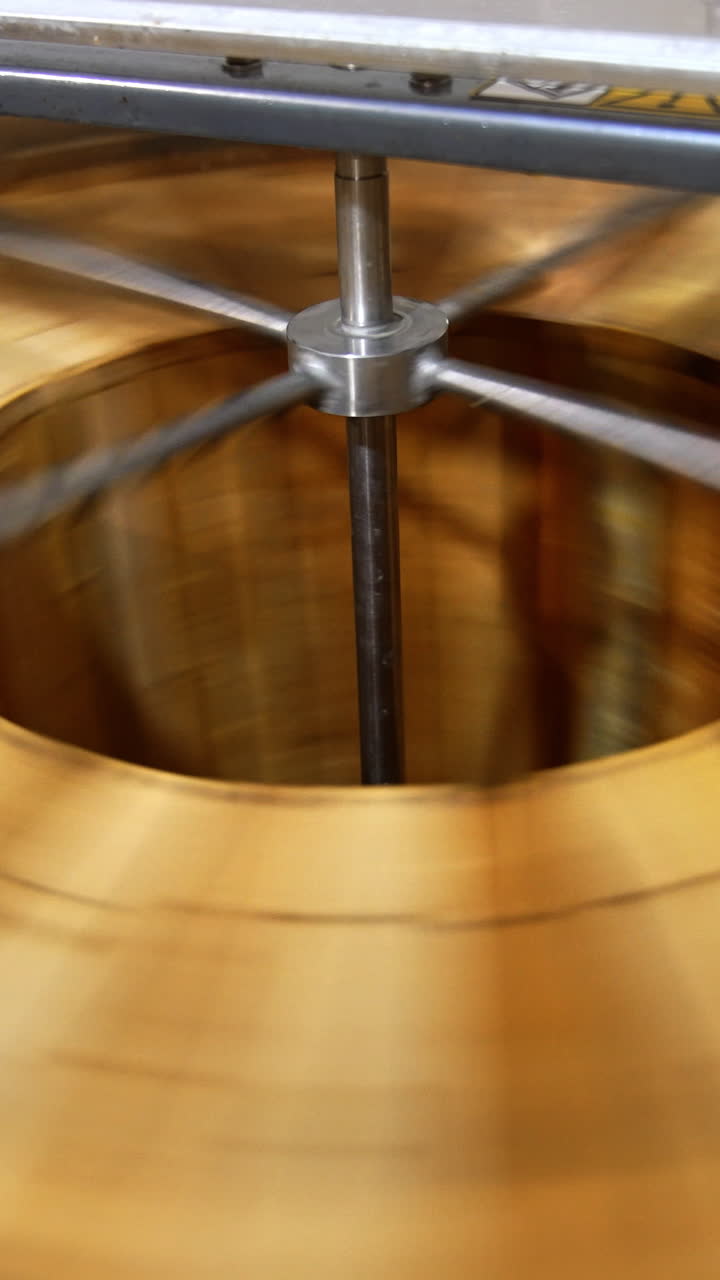 Quick rotation of honey frames inside the centrifuge. Wooden frames with honey combs spin to shake off liquid honey. Top view. Vertical video