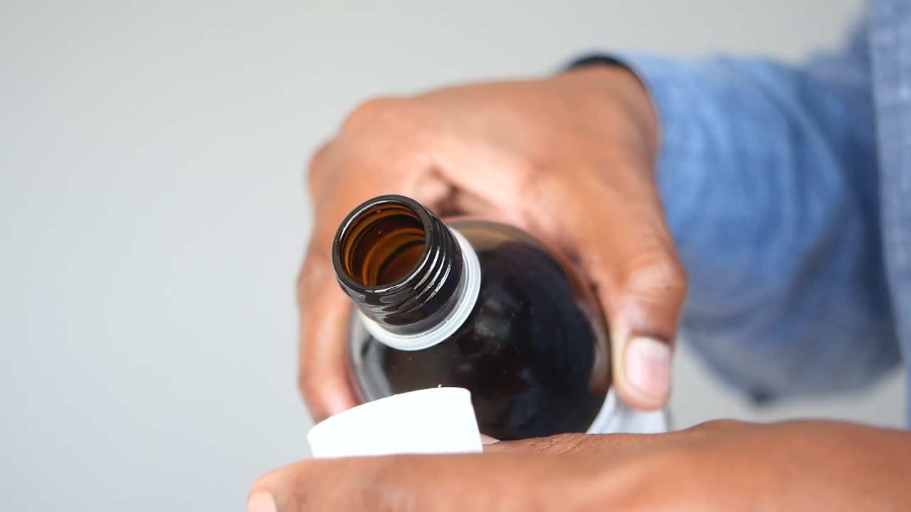 persona vertiendo medicina de una botella