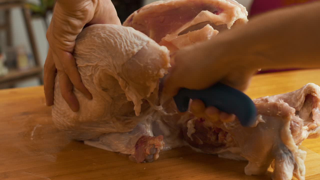 나무 절단 보드에 칼로 칠면조 고기를 도살하는 요리사의 손에 가까이