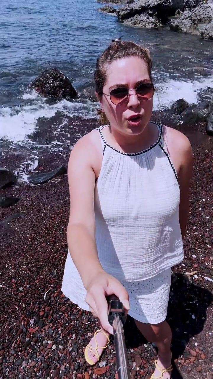 Influencer che fa vlogging sulla spiaggia rossa a Santorini, Grecia