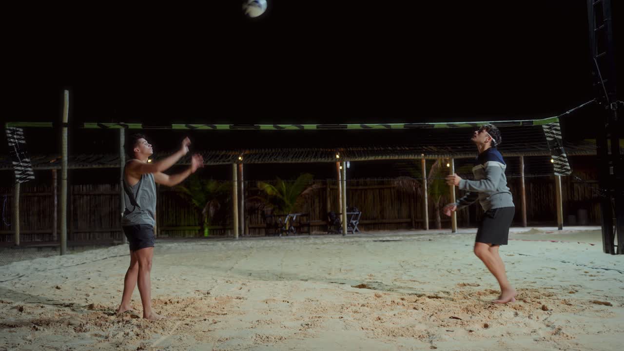 Two Men Playing Beach Volleyball at Night