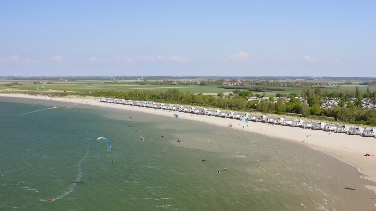 바람이 부는 날 네덜란드 비센케르케 근처 해변에서 연습하는 카이트서퍼 그룹의 공중 후방 설정 샷