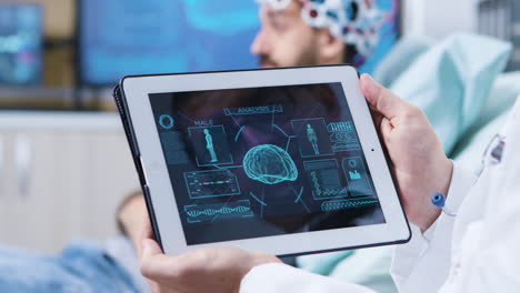 doctor in a modern clininc holding tablet with brain analysis