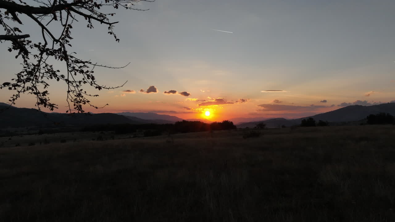 puesta de sol detrás de un árbol solitario en una meseta montañosa
