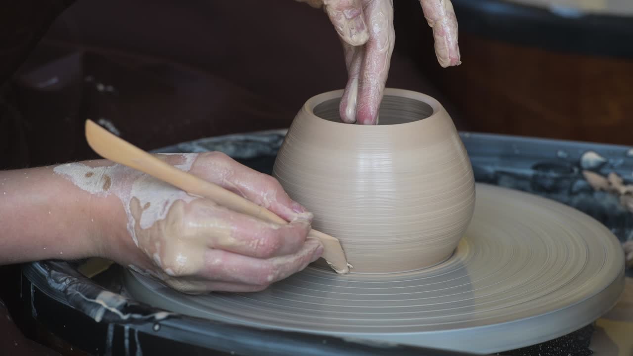 primer plano de un ceramista irreconocible formando un jarrón de arcilla hecho a mano usando una herramienta especial y un círculo de alfareros