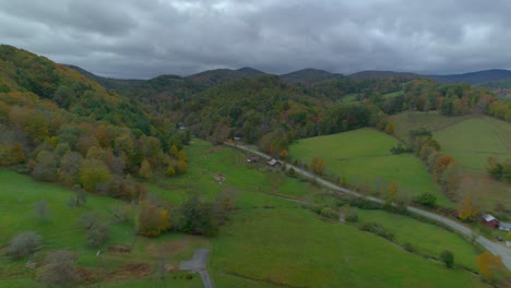 Drone-soaring-above-countryside-homes-in-the-lush-green-mountains-in-early-fall