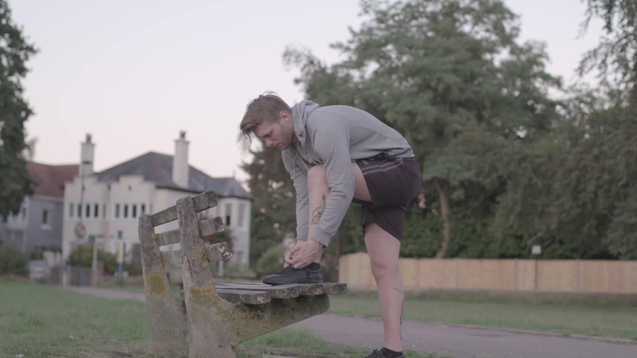 Man tying shoelaces on a bench