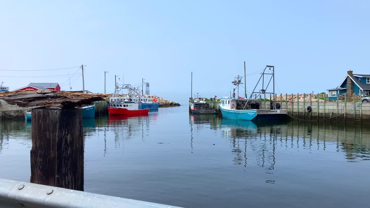 High tide with fishing boats in Halls Harbour, Nova Scotia, Canada on calm reflective water