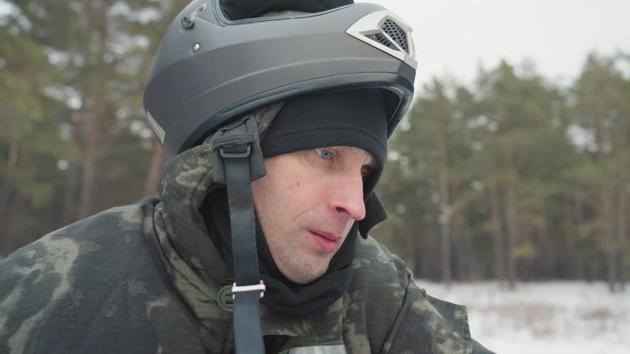 Rider ready on snowmobile, blowing vapor and scanning trail ahead in winter pine forest helmeted man grips handlebars, focused expression, engine noise implied, snow and powder around windshield