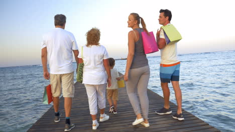 big family with shopping bags on pier in the sea