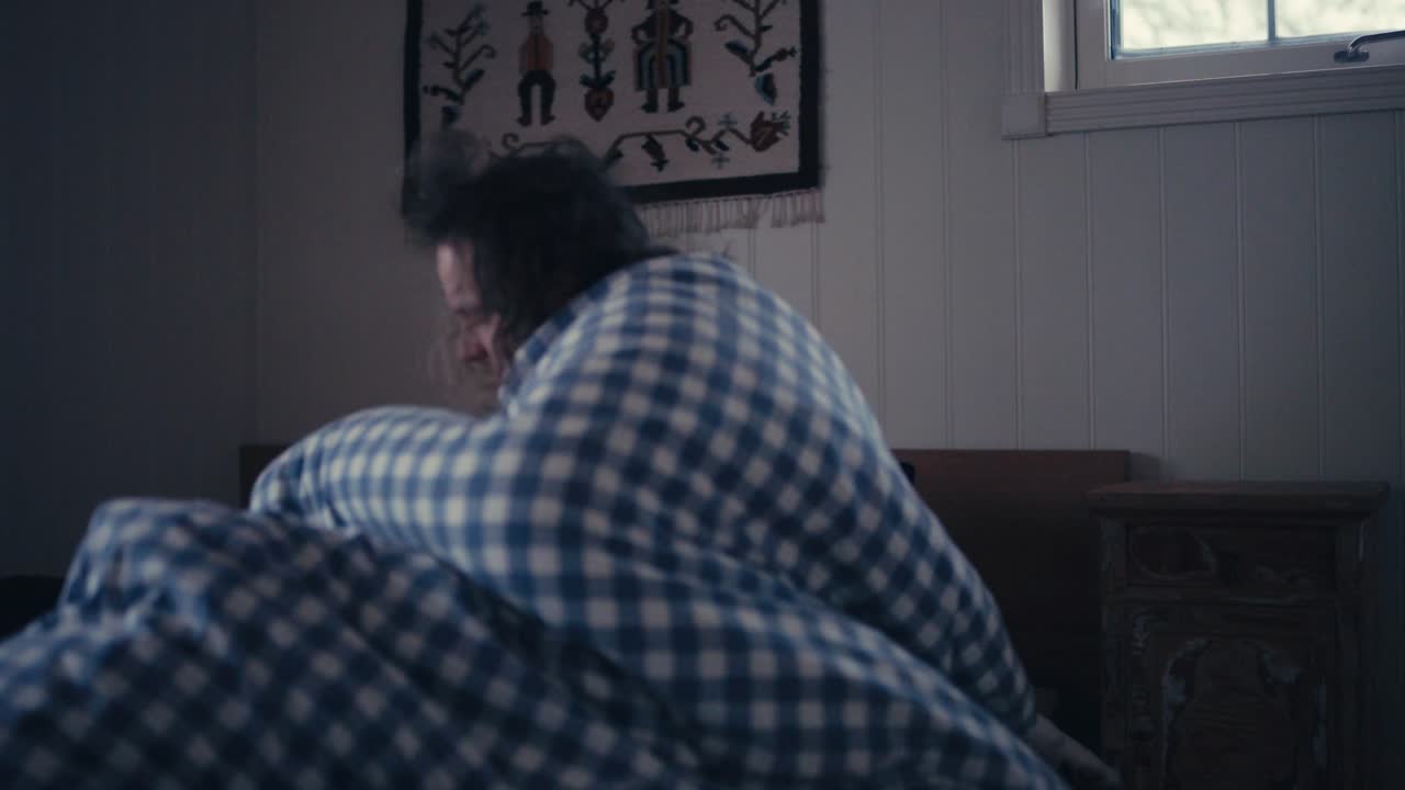 침대에서 자고 있는 남자는 집에서 사랑스러운 애완용 알래스카 말라뮤트 개와 함께 깨어납니다