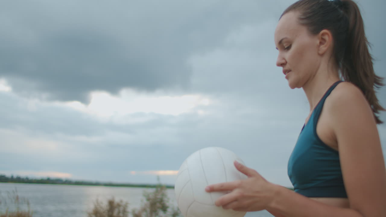 sirve en voleibol de playa joven jugadora está sosteniendo la pelota en las manos vomitando y golpeando retrato medio