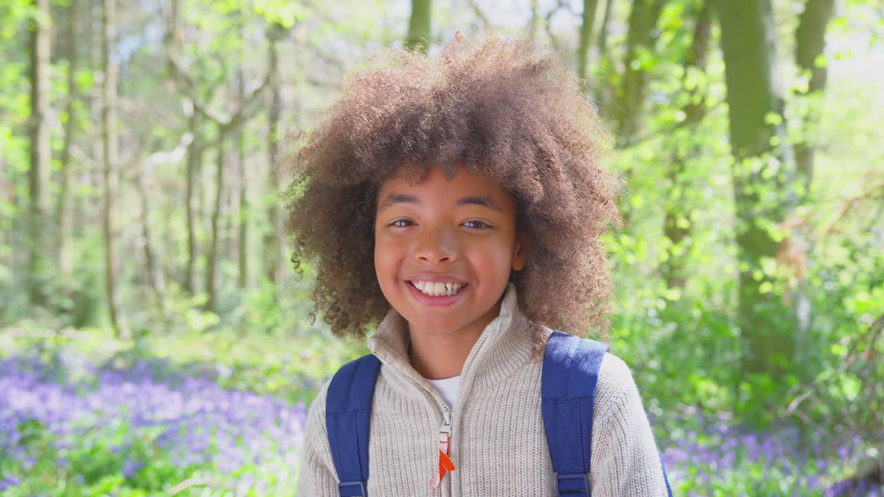 retrato de un niño sonriente caminando en los bosques de primavera con campanas azules