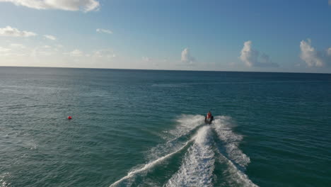 Aerial-back-view-follow-woman-jet-skier-riding-on-caribbean-coast-have-fun,-enjoy-holidays,-try-water-sports