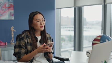 hipster girl pondering cellphone at bright room closeup. blogger looking windows