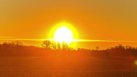 toma estática del sol saliendo sobre el cielo amarillo en un lapso de tiempo sobre el pasto del granjero al amanecer