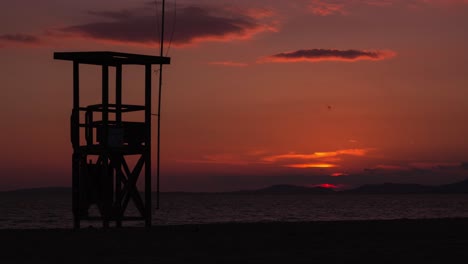 Hermoso-Lapso-De-Tiempo-De-Puesta-De-Sol-De-4k-En-Una-Playa-Con-Una-Torre-De-Salvavidas-En-Primer-Plano-Y-La-Puesta-De-Sol-En-El-Fondo-En-El-Mar-Mediterráneo---Mallorca,-España