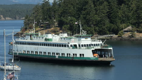 vehicle ferry sailing through harbor near pine trees