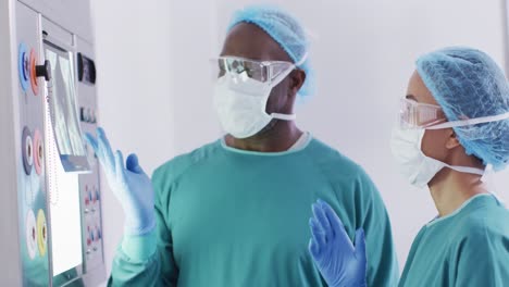 video of diverse male and female surgeon discussing x-ray before operation in operating theatre