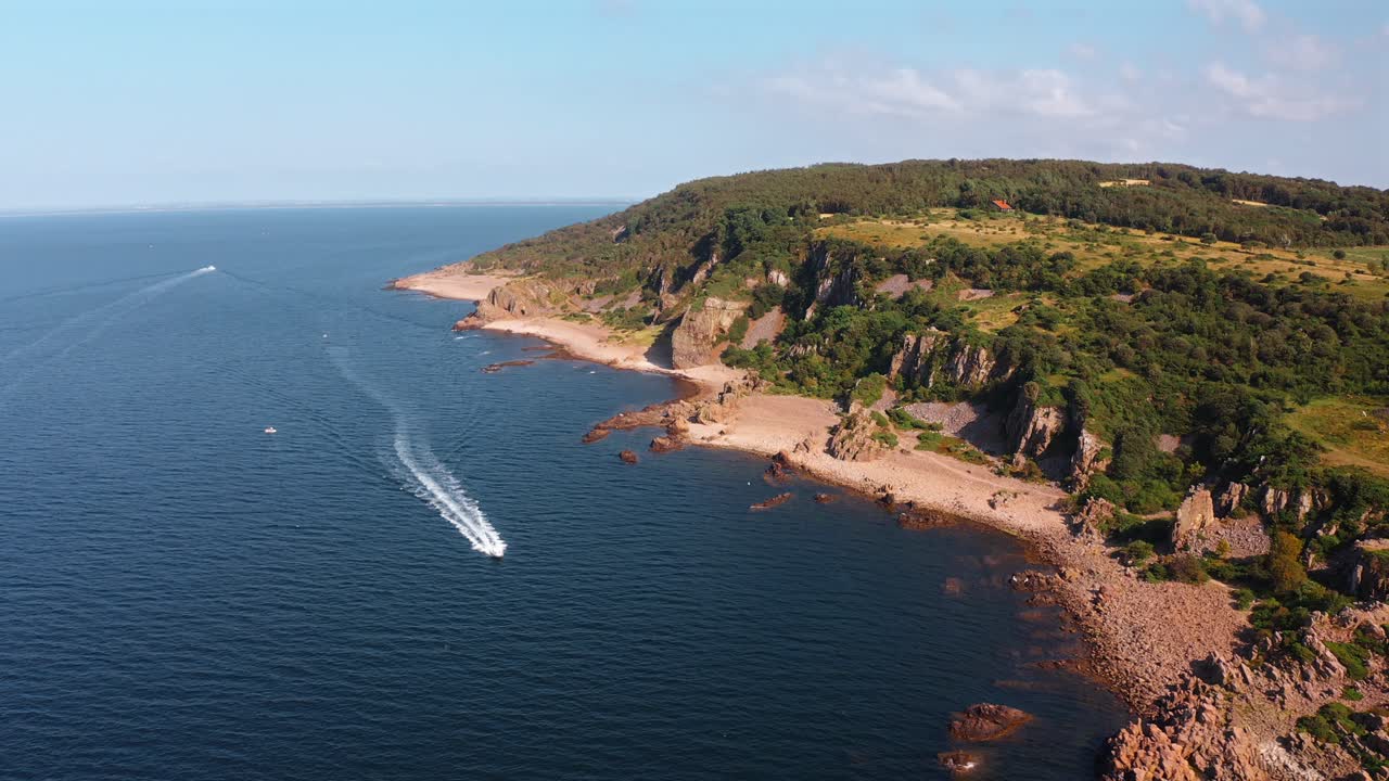 Aerial shot of a coastal landscape, calm water, and scenic rocky cliffs at Hovs Hallar