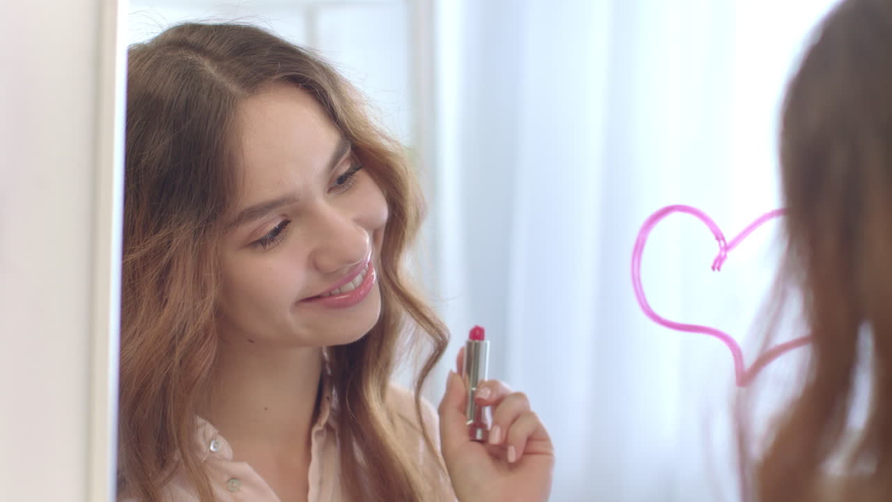 mujer romántica dibujando un corazón en el espejo con lápiz labial. concepto del día de san valentín