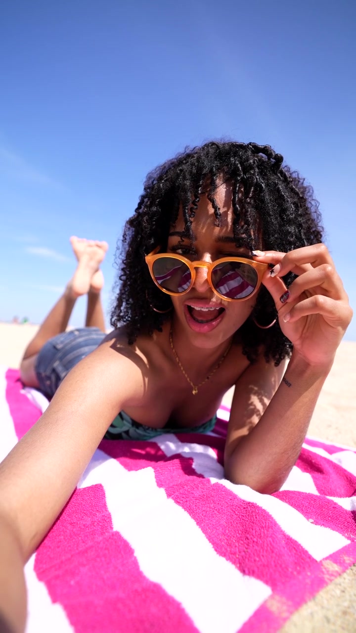 Young Woman with Braces and Sunglasses Posing for a Selfie on the Beach