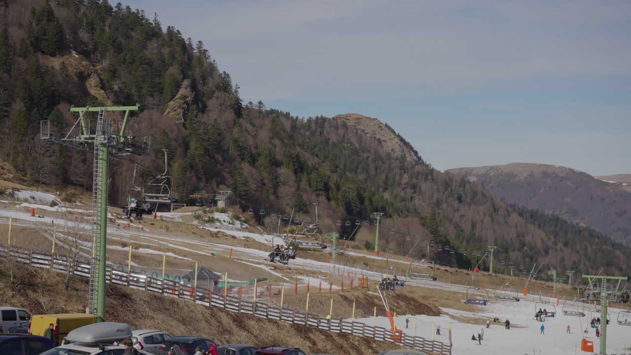Chairlift in a ski resort in France, patches of snow, people equipped.