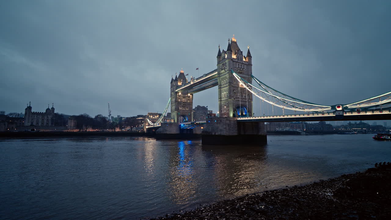 Tower Bridge hämärässä rauhallisella jokimaisemalla ja kaupungin valoilla