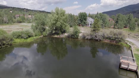 aerial video of a pond in trent park in silverthorne, colorado. camera stats low and rises up.