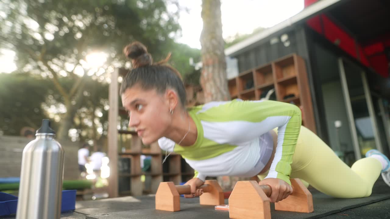 Mujer joven haciendo flexiones de rodillas en un gimnasio al aire libre