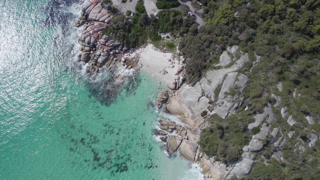 pequeña playa de arena en medio de la costa rocosa de vegetación del arrecife de sloop en la bahía de binalong, tasmania