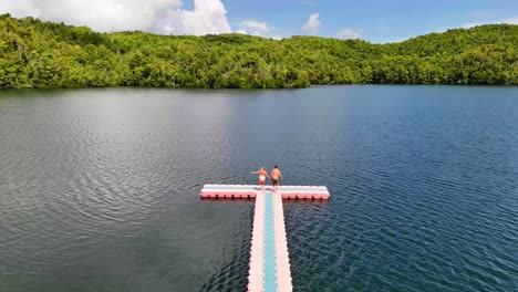 still 4k drone video of a couple running along a platform and jumping into a beautiful lake in the banggai islands, indonesia. this is a unique lake containing stingless jellyfish where you can swim