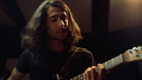 emotional musician playing guitar in studio. composer producing music indoor.