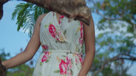 Movimiento-De-Cámara-Descendente-De-Una-Chica-Latina-De-Pelo-Rojo-Con-Un-Largo-Vestido-De-Flores-En-El-Parque