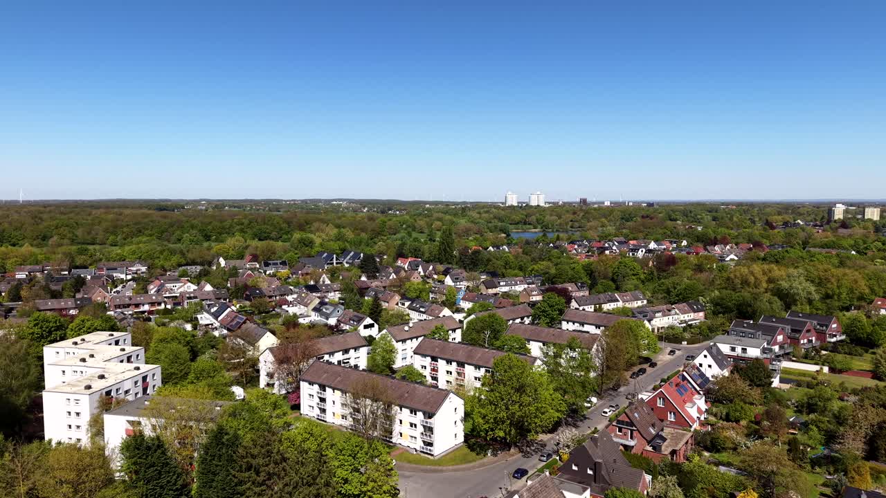 Luchtfoto met drone van een vredige stadswijk in de lentezon, met appartementencomplexen voor meerdere gezinnen, vrijstaande huizen, met bomen omzoomde straten en een rustig residentieel landschap in de buitenwijken. Breedbeeldopname.