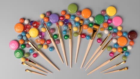 paintbrushes and colorful paint pods arranged on a grey background