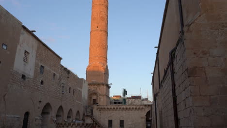 turkey, mardin, ulu cami mosque's minaret from top to down. some people spread around the courtyard of the mosque dated 1176. yellow stoned minaret standing over one thousand years.