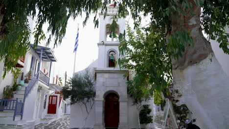 Eine-Atemberaubende-Weiße-Griechische-Kirche-Wird-Von-Einem-Baum-In-Mykonos,-Griechenland,-Verdeckt